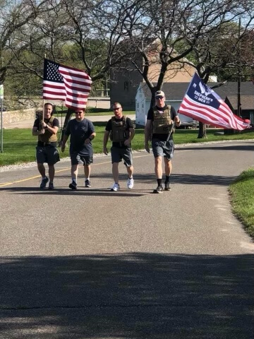 Shepherd's Mens group jogging while wearing military vests and holding flags.