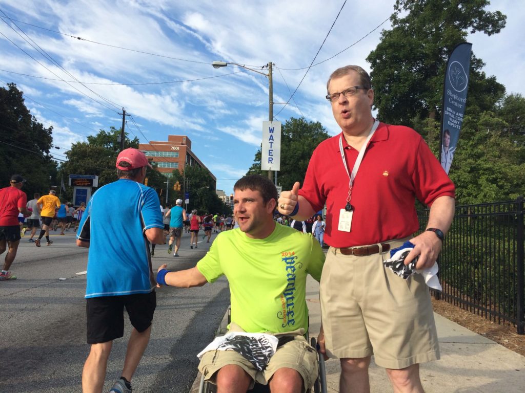 Two men cheering on runners at the Peachtree Road Race in Atlanta.
