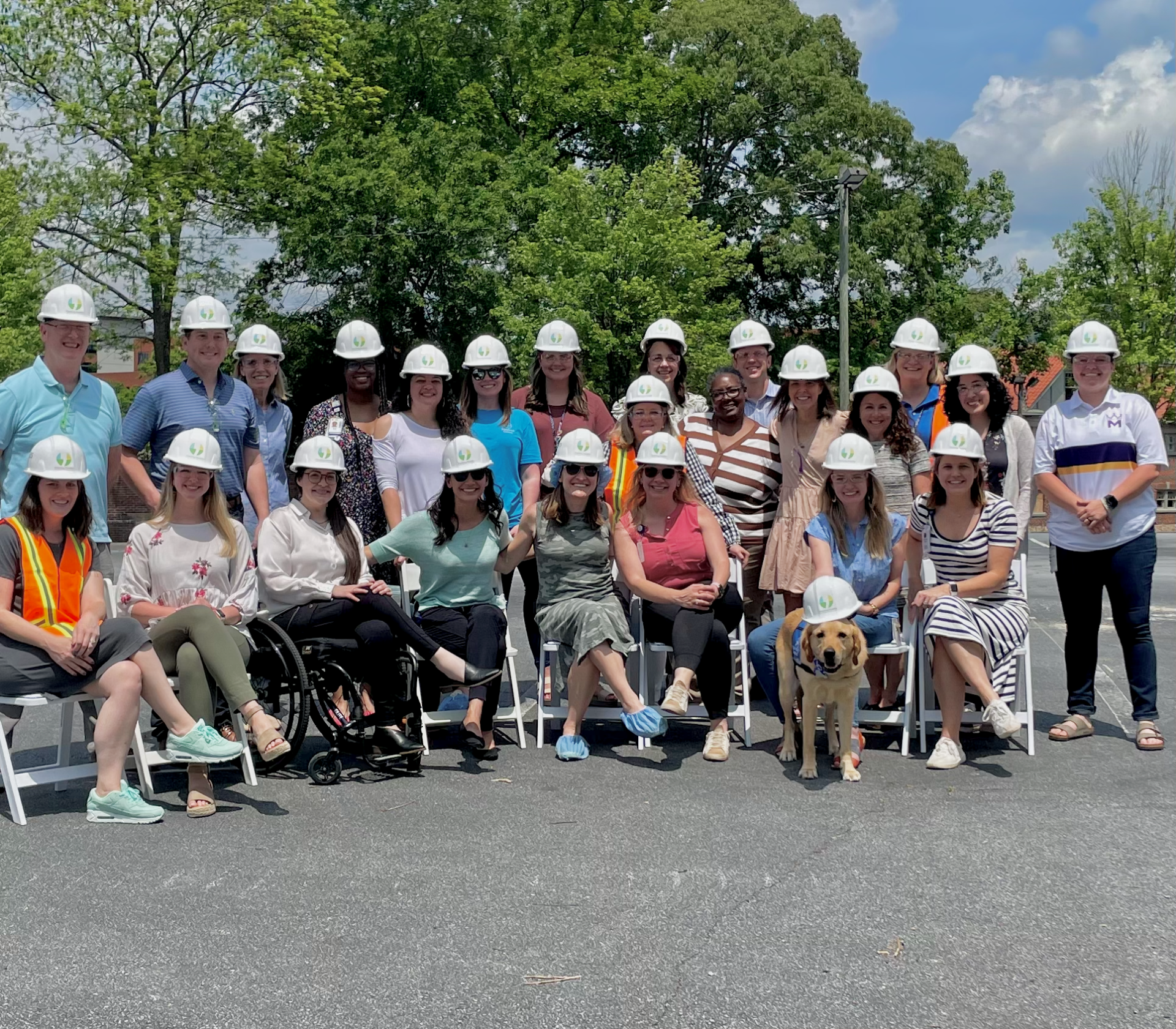 The Shepherd Center Foundation team and therapy dog, smiling and wearing Pursuing Possible branded hard hats.