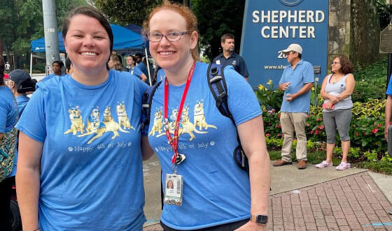 Two women and therapy dog smiling outside of Shepherd Center during Shepherd's Fourth of July celebration.