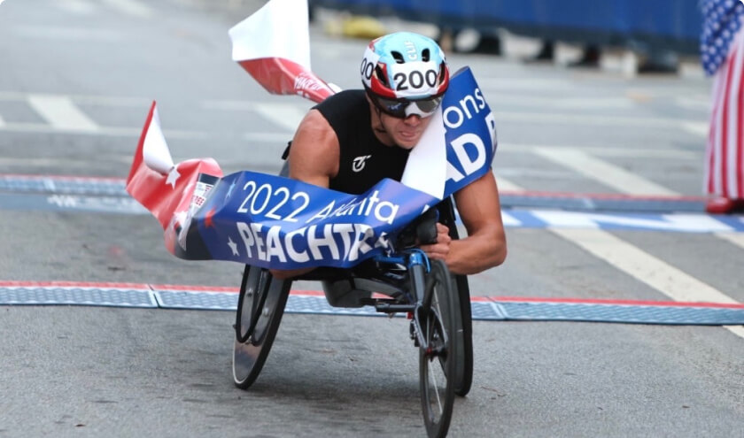 Man crossing the finish line at Shepherd Center's Wheelchair Division of The Peachtree Road Race.