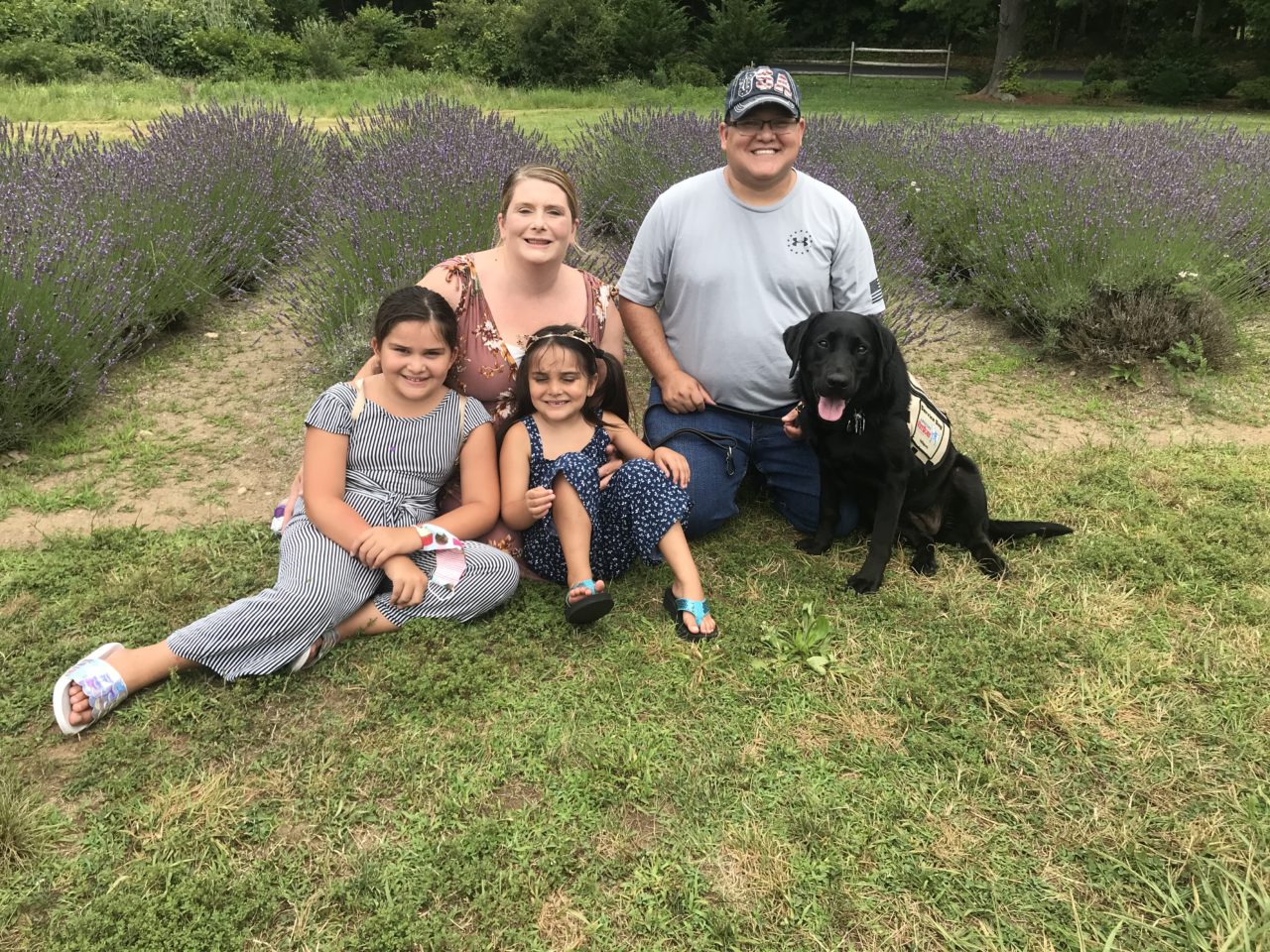 Family smiling with their therapy dog during an outing to a lavender farm.