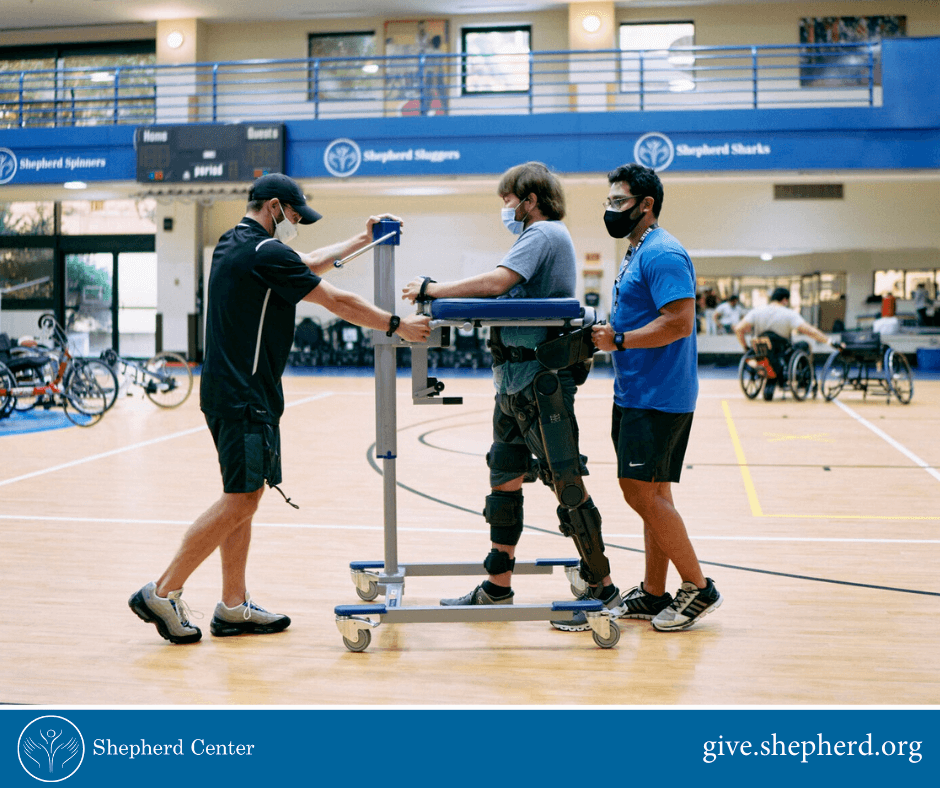 Shepherd patient using standing mobility device in gymnasium