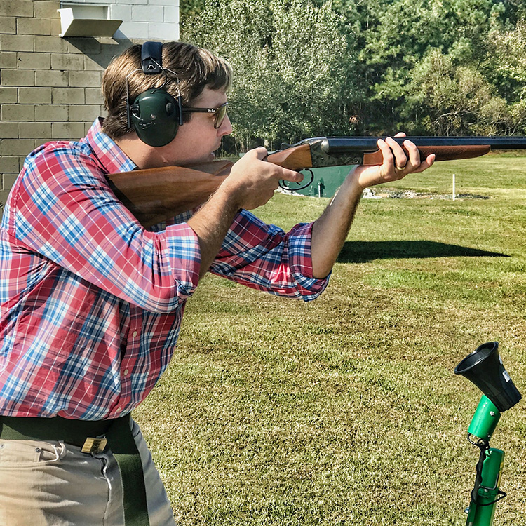 A man holding a rifle participates in clay shooting.