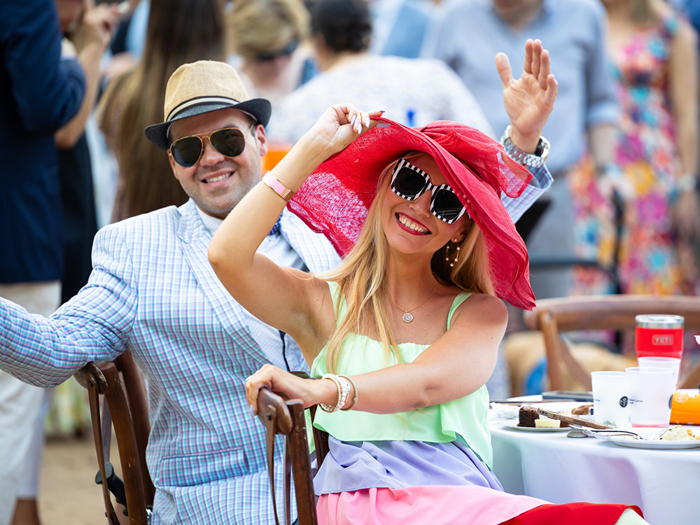 A smiling man and a woman are seated at a table at Derby Day.