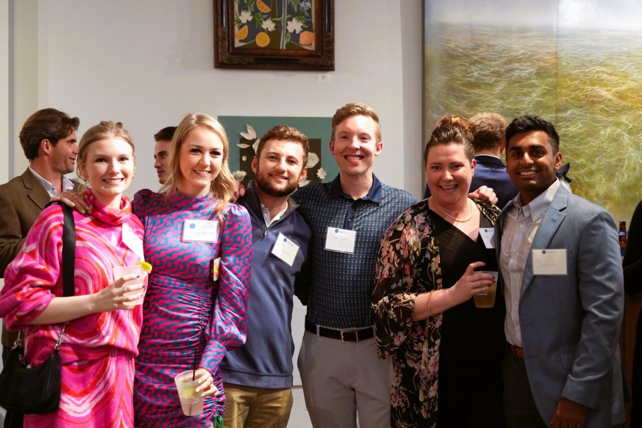 Seven members from the Shepherd Center Junior Committee board pose for a photo at a networking event in a local art gallery in Atlanta