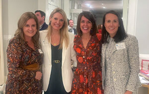 Four women from the Impact Council smile for the camera at a networking event.