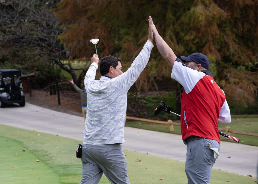 Two golfers high-five on a golf course.