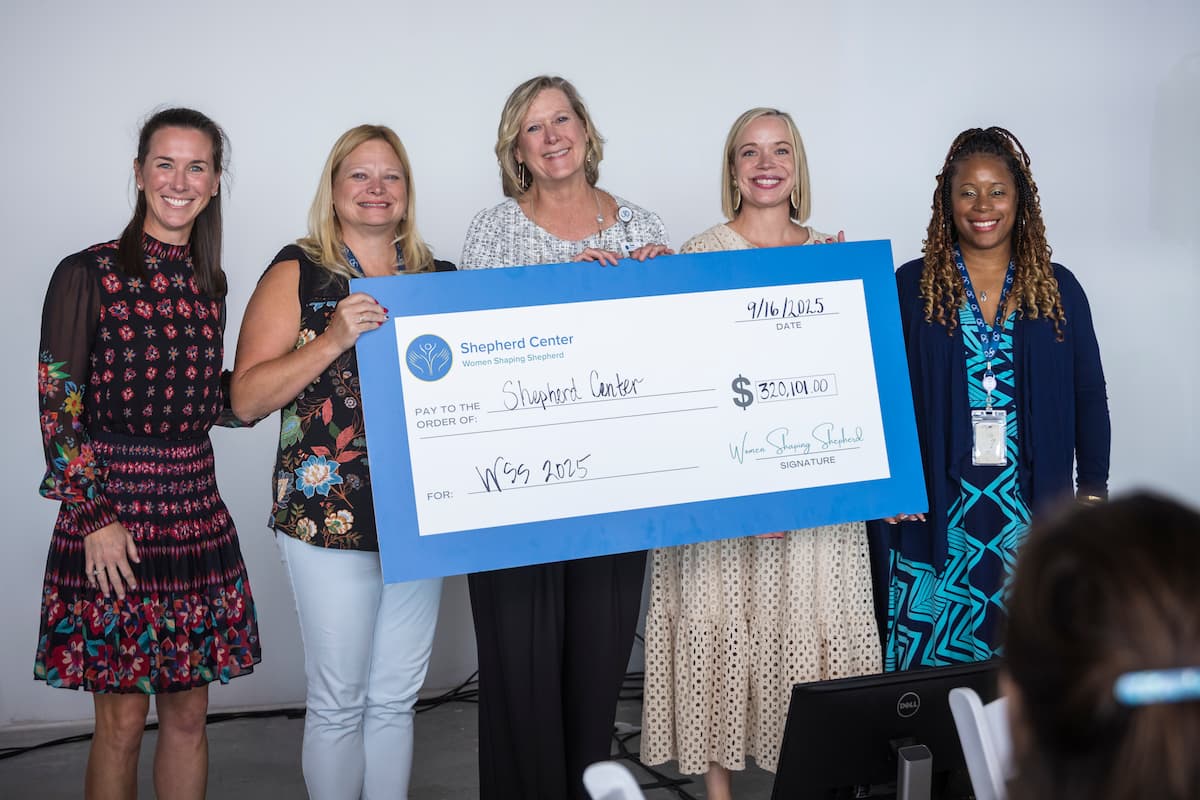 Five women stand together holding a large ceremonial check for $320,101 made out to Shepherd Center.